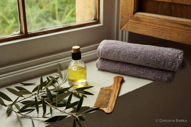 Rituel beauté : flacon d’huile d’olive, peigne de bois et linge